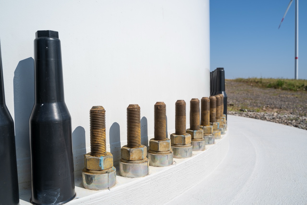 Close-up of large bolts securing the foundation of a wind turbine